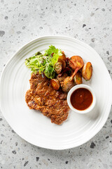 A perfectly pan-fried pork schnitzel is served with crispy roasted baby potatoes, a fresh green salad, and a side of savory red sauce on a white plate