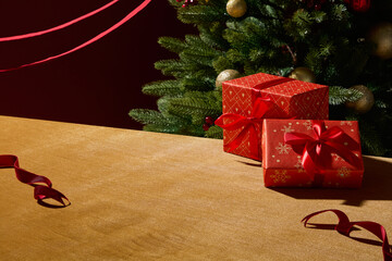 Red Christmas presents placed on table with a cozy festive background. The simple composition and warm light make it ideal for holiday promotional layouts. Space for design