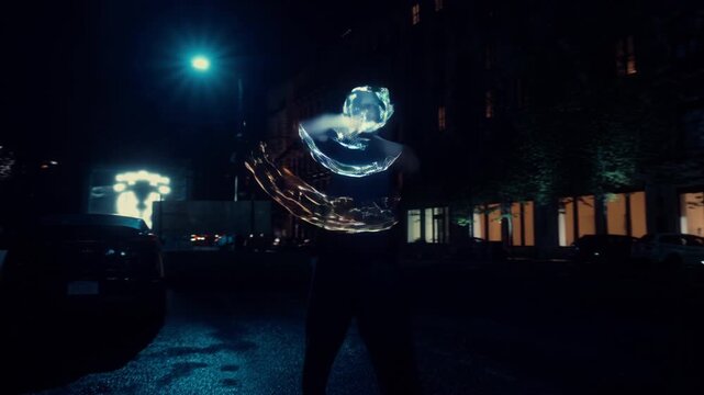 A talented performer captivates onlookers with dazzling light tricks in a lively city street at night, surrounded by buildings and streetlights