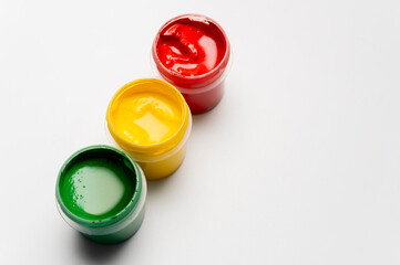 Jars of multi-colored gouache on a white background. Green, red, and yellow traffic light colors.