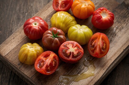Warm morning light reveals vibrant heirloom tomatoes arranged beautifully across a rustic wooden board