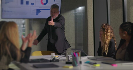 Angry business executive yelling during office meeting with team as colleagues react in shock near data screen in boardroom