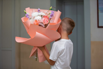 Young boy surprises someone special with a large bouquet of flowers in a hallway