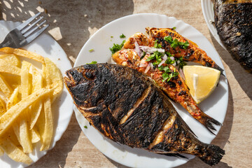 El Jem, Tunisia A plateof barbequied fresh fish with lemon and french fries.