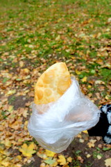 A woman's hand holds a fried, greasy bun in a bag.