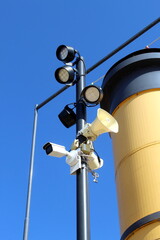A loudspeaker, a CCTV camera and a lamp hang on one pole.