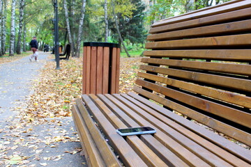Someone forgot a cell phone on a bench in the park in autumn.