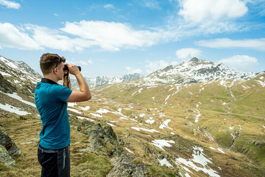 Male hiker observing alpine landscape with binoculars at Passo Gavia - Powered by Adobe