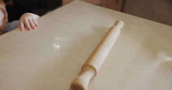 Little boy rolls a rolling pin on the table. Video with audio.