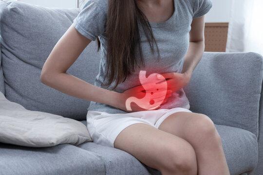 Gastroesophageal Reflux Disease. young woman suffering stomach ache sitting in living room at home, food poisoning, people painful stomachache, gynecology, menstrual pain, medical health care concept