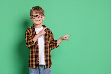 Cute boy in glasses on green background, space for text