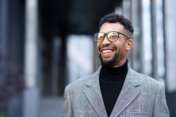 Fototapeta premium Smiling man in glasses and suit on city street. Space for text