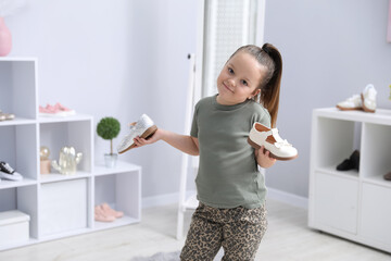 Little girl choosing between different shoes at shop