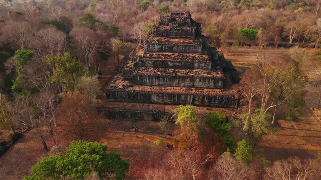 Aerial view of the ancient stone pyramid of koh ker temple complex, surrounded by dry jungle forest, Cambodia.