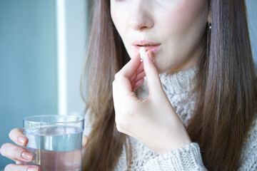 Naklejka premium Woman holding glass of water and white pill.
