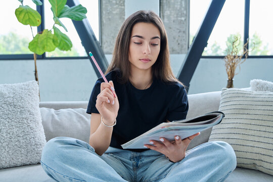Webcam view of teenage girl student with textbook studying online remotely, video lesson - Powered by Adobe