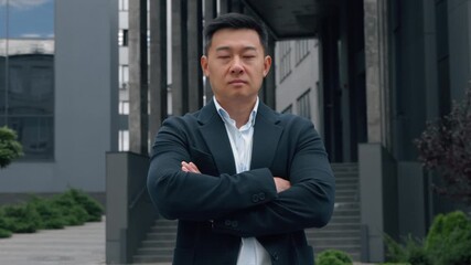 Motivated serious 40s Chinese ethnic business man crossing hands looking at camera Japanese middle-aged businessman adult Asian Korean male entrepreneur formal manager crossed arms power pose in city