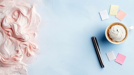 A flat lay composition on a light blue textured surface features a white mug of coffee with whipped cream, a silver pen, and colorful sticky notes, alongside a