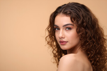 Young woman with curly hair posing in a soft beige studio portrait, serene confident gaze. Generative AI