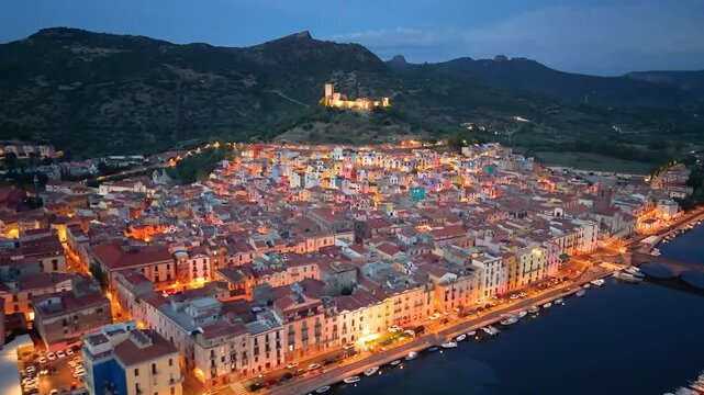 cinematic aerial shot capturing italian heritage site with illuminated streets and flowing river. Bosa. Italy