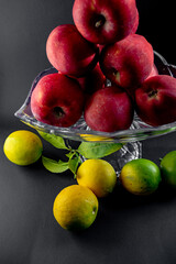 Still Life with Red Apples and Lemons in a Glass Vase on Black Background