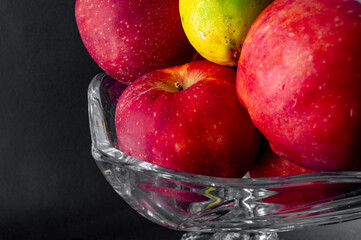 Still Life with Red Apples and Lemons in a Glass Vase on Black Background