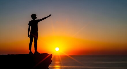 Fototapeta premium Silhouette of a Person Standing on a Cliff at Sunset