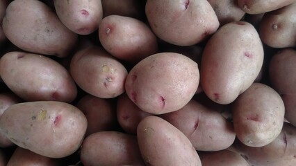Fresh raw potatoes with natural skin texture, piled in a market display. Close-up organic potatoes perfect for food background, agriculture, farming, and vegetable concepts