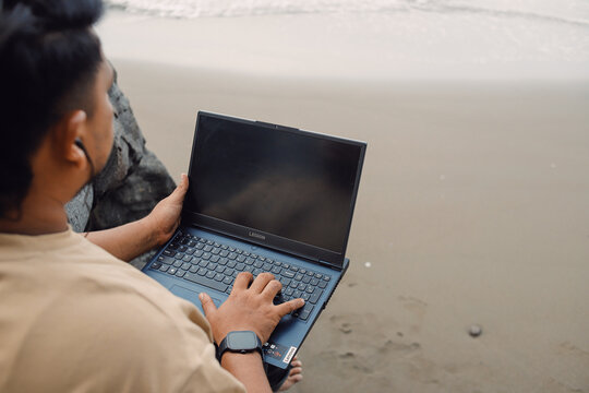 Man Working on Laptop by the Beach – Remote Work, Digital Nomad Lifestyle, Freelance Productivity and Online Work Concept in Natural Coastal Environment