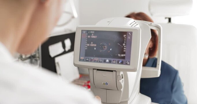 Female optometrist makes eye examination using auto refractor machine, closeup