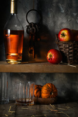 Apples, small pumpkins and a bottle of cognac on a shelf in an old pantry