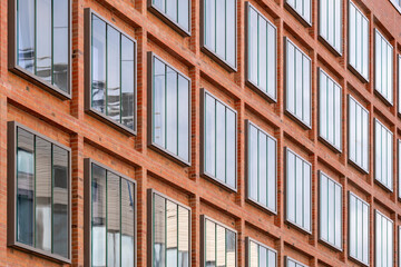 Commercial architecture facade design highlighting geometry, a controlled grid and pattern within strong structure and contrast, enhanced by a vivid red stripe and rhythmic detail.