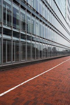 A striking architecture facade visual built on texture, repetition and shadow, featuring structure and contrast with a prominent red element supported by dynamic lines and minimalism.