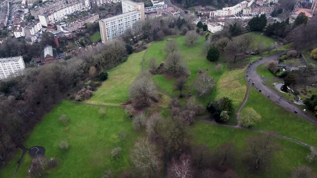Aerial view over Brandon Hill, Bristol, UK. Moving slowly over the park on a cloudy rainy day. People walk along the pathways among the bare trees.