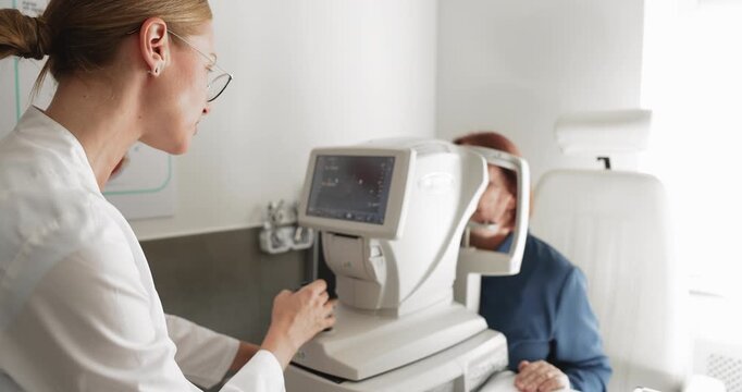 Optometrist operating autorefractor machine during eye examination for elderly patient