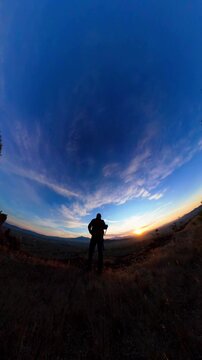 Hiker sitting on a hill watching the sunrise over mountains