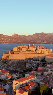 Aerial view of calvi citadel at sunrise with serene waters. Fortress with marina. Corsica. France
