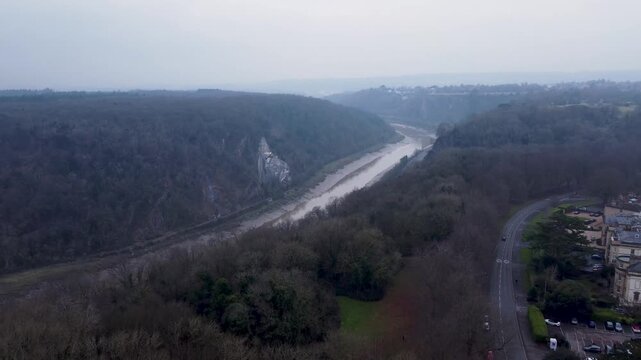 Misty afternoon over Clifton, flying slowly over road and woodland towards a very murky and muddy river avon