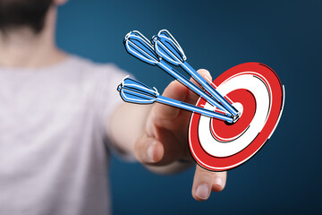Concept of success and achievement. Hand holding a target with darts hitting the bullseye,...