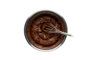 A high angle shot of a big mixing bowl packed with chocolate dough mix, along with a wire whisk, all set against a white background.