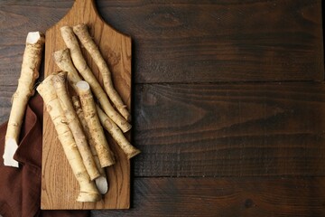 Fresh raw horseradish roots on wooden table, top view. Space for text