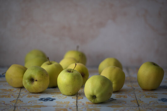 Yellow apples placed on patterned tiles, great for food-related projects, product presentations and farm-to-table marketing.