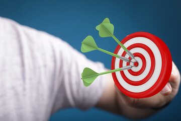 Close-up shot of hand holding target with three darts in the bullseye. Concept of success,...