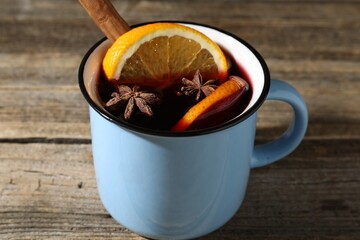 Tasty mulled wine in mug on wooden table, closeup