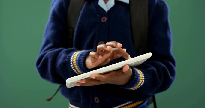 Tapping school student in navy cardigan and white collared shirt, holding white tablet and backpack