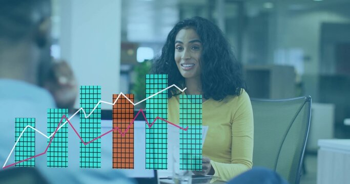 Presenting woman in yellow top holding documents and speaking in open-plan office, overlaid charts