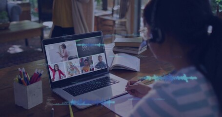 Writing in notebook child in striped top wearing headphones watching laptop at home, copy space