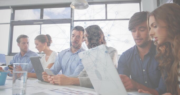Meeting six staff reviewing laptops tablet charts in office wearing business casual with data layer