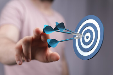 Close-up of a person aiming at a dartboard, representing hitting a target, achieving goals, and...