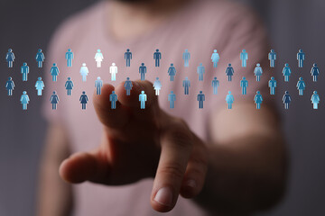 Person's hand touching digital icons symbolizing global connection and networking. This stock image...